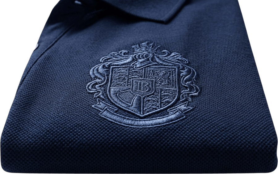 Escudo bordado en hilo sobre un polo azul marino, detalle de las puntadas